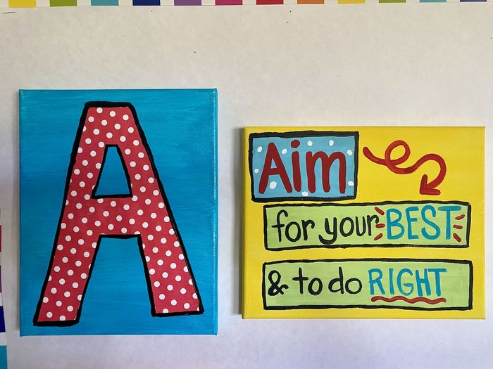 Two painted canvases, on the left a large red letter A with white polka dots. On the right the phrase 'Aim for your best and to do right'
