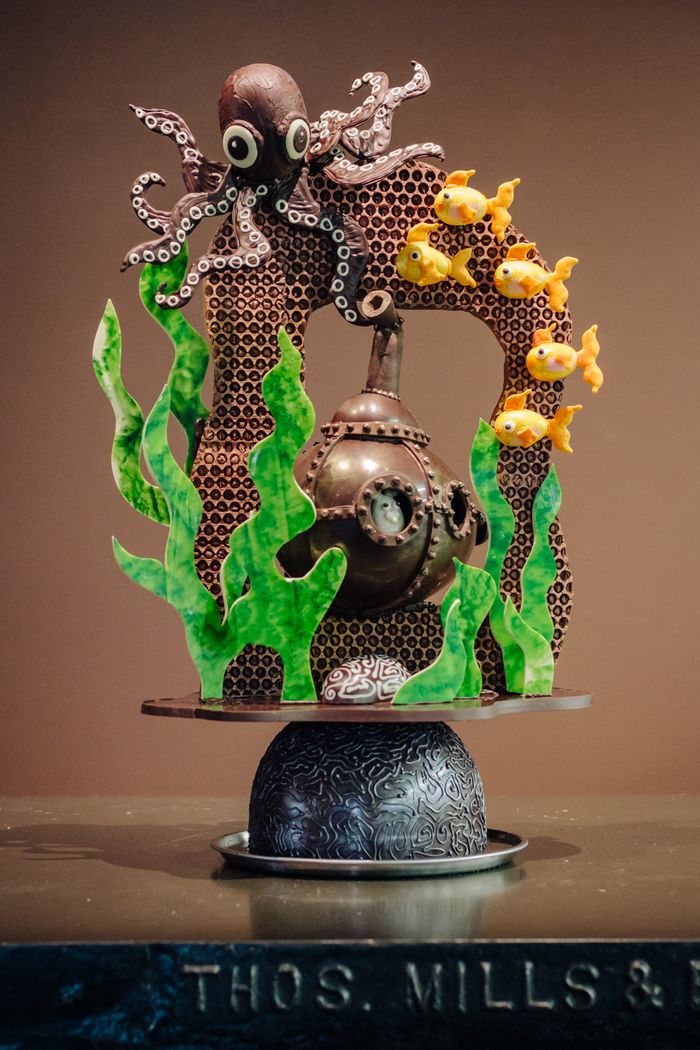 A large Easter chocolate sculpture depicting an underwater scene with a bunny riding in a submarine through a brown coral reef. A large octopus sits on the upper left of the reef.