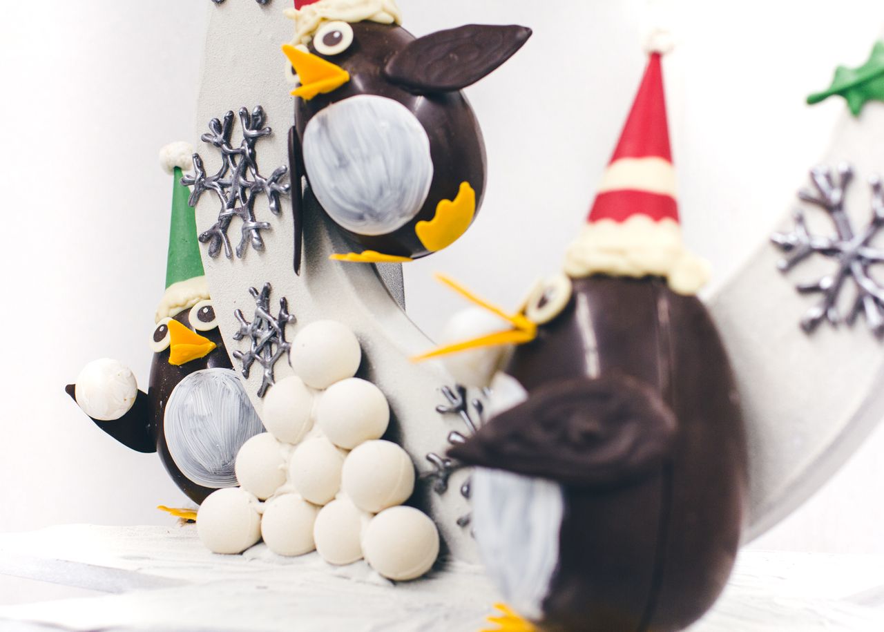 Close-up of chocolate penguins having a snowball fight. The penguin on the left is partially obscured and looks like they're just about to throw a snowball.