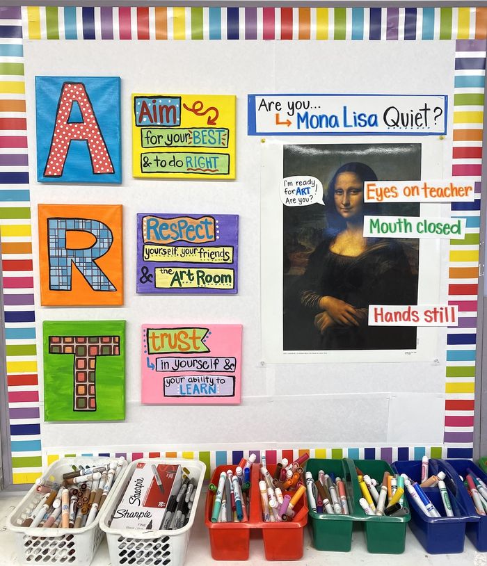 An informational board in a classroom with a rainbow of coloirs around the edge. On the left are big letters spelling out A R T and on the right is a sign asking the kids if they are Mona Lisa Quiet